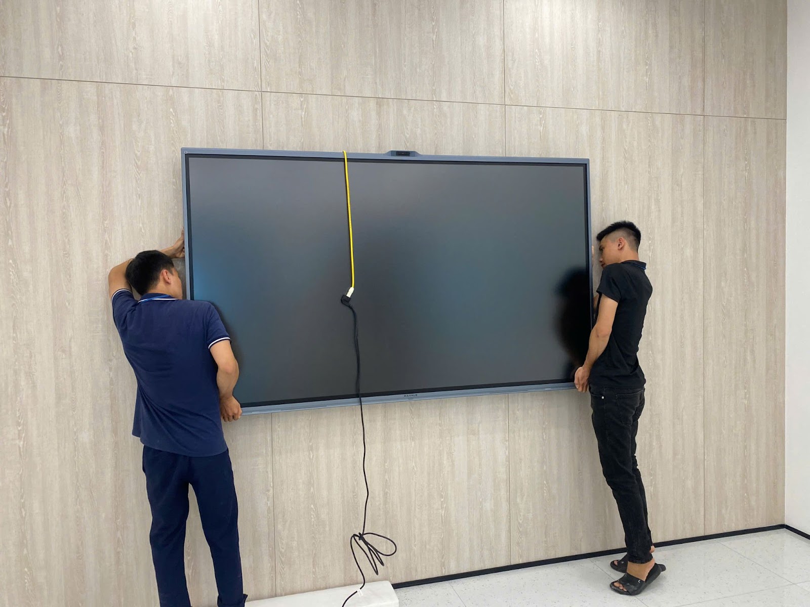 Kỹ thuật viên treo màn hình lên khung treo